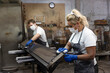 © Emma Innocenti/Westend61 - Carpenters applying varnish on wood with cloth while standing in factory