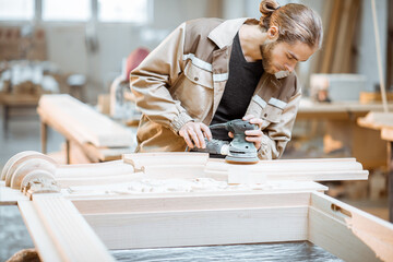 Wall Mural - Carpenter grinding joinery product with carvings, finishing woodwork at the carpentry manufacturing