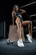 © andy_gin - Tall athletic woman posing in the gym on a bench with dumbbells. Fitness and bodybuilding concept.