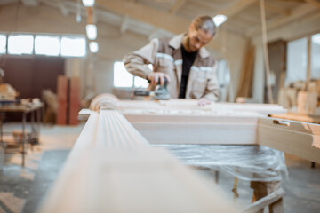 Wall Mural - Carpenter grinding joinery product with carvings, finishing woodwork at the carpentry manufacturing