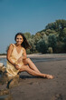 © Mareen Fischinger/Westend61 - Mature woman sitting on rock at beach during sunny day