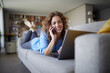 © Rainer Berg/Westend61 - Smiling woman talking on mobile phone while lying on sofa at home