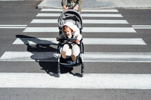 Mother With Son In Baby Carriage Crossing Street In City On Sunny Day