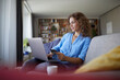 © Rainer Berg/Westend61 - Smiling woman doing online shopping on laptop at home