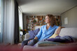 © Rainer Berg/Westend61 - Smiling woman looking away while sitting on sofa at home