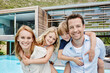 © Roger Richter/Westend61 - Smiling family standing against modern house