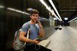 © VALENTINA BARRETO STUDIO/Westend61 - Handsome young man talking on phone holding digital tablet while looking away at illuminated subway