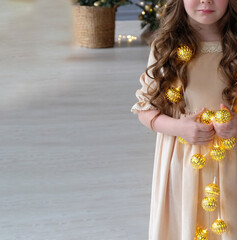 Canvas Print - girl and Christmas glowing garland. A little girl is stay on the floor. Girl holding a garland with glowing stars in her hands