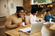 © Drazen - Happy black father drinking tea while having video call over laptop at home.
