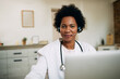 © Drazen - Happy African American doctor with headset working on laptop at her office.