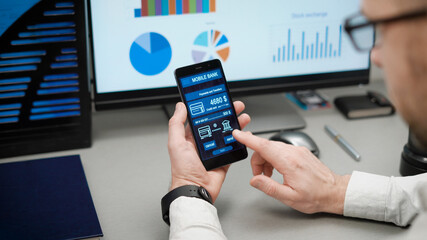 Counter payment via mobile banking application on the smartphone. A man transfers money from his credit card to another person.