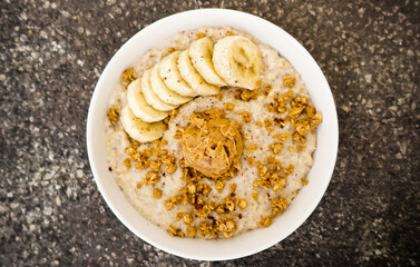 Wall Mural - Top view closeup of an oatmeal  with bananas, nuts, and peanut butter on a bowl