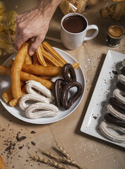 Canvas Print - Hand-picking up a churro from the table plate with a cup of chocolate.