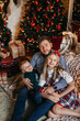 © Oleksandr - Close up overjoyed family unpacking Christmas gifts, happy father with adorable little daughter and son wearing sweaters sitting on warm floor near decorated festive tree at home