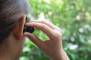 Close up of woman is using the black true wireless earbuds by hand to put in ear and control