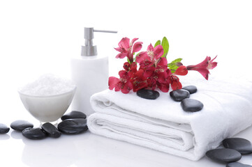 Wall Mural - spa concept with stones,red flowers on towel with essential oils


