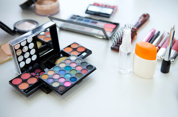 Female decorative cosmetic with lipstick and eyeshadow palette on the table