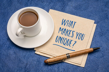 Wall Mural - What makes you unique? Handwriting on a napkin with a cup of coffee. Personal branding and development concept.