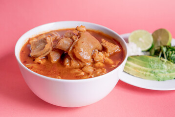 Wall Mural - Exquisite Mexican Menudo on a white plate accompanied by a dish with condiments on the back.