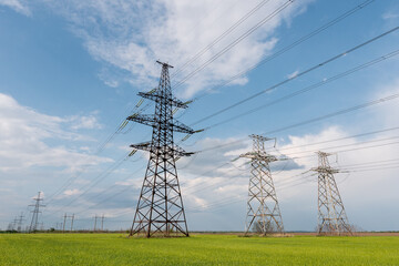 Wall Mural - high voltage lines and power pylons and a green agricultural landscape on a sunny day.