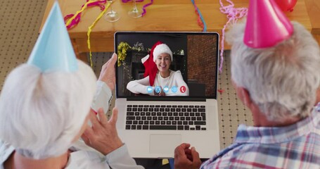 Poster - Caucasian senior couple wearing party hats on laptop video chat during christmas at home