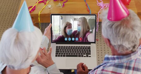 Poster - Caucasian senior couple on laptop video chat wearing party hats at home