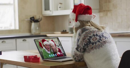 Poster - Caucasian woman wearing santa hat on laptop video chat during christmas at home