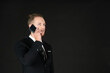 © Arunporn - Portrait of young smart confident and successful businessman in black suit using smartphone isolated on black background