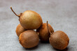 © Maarten Zeehandelaar - Bunch of tiny kiwifruit of Actinidia Deliciosa Setosa species on a textured surface gray kitchen background