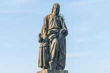 An Outdoor Statue Of St Joseph With A Young Christ, On The Charles Bridge, Prague. He Holds A Flowering Rod. The Sky Behind Is Blue