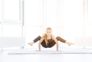 Beautiful girl doing yoga asana in bright room