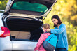 © Ievgen Skrypko - Mother and daughter before lessons at school near open car trunk outdoors