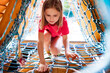 © Ievgen Skrypko - Little girl climbing throught net on playground in park