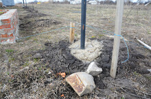 Building A Fence: Cementing A Metal Fence Post Into The Ground By Pouring The Concrete Into The Fence Post Hole.