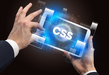 Poster - Close-up of a hand holding tablet with CSS abbreviation, modern technology concept