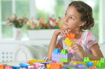 Poster - Little girl playing with colorful plastic blocks