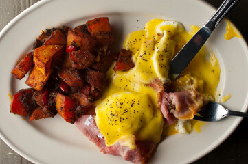 Wall Mural - Eggs Benedict. Traditional classical American diner or French Bistro brunch item. Homemade Hollandaise sauce drizzled over a poached egg, country ham on top of a toasted English muffin.  