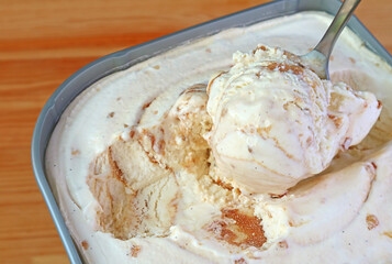 Closeup of a Spoon Scooping Delectable Caramel Macadamia Nut Ice Cream in the tub