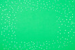 Green festive background with shining silver confetti in shape of stars. Frame with copy space