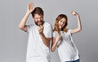 © SHOTPRIME STUDIO - cheerful man and woman in headphones listen to music and dance on a gray background