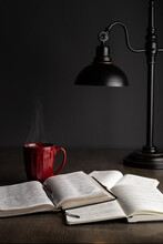 Bible Study With Notes, Book Of Prayer, And Red Coffee Mug Under A Lamp.
