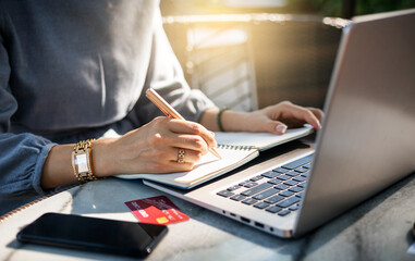 Close up. Young businesswoman working with computer laptop and writing note while she working outdoor in the park