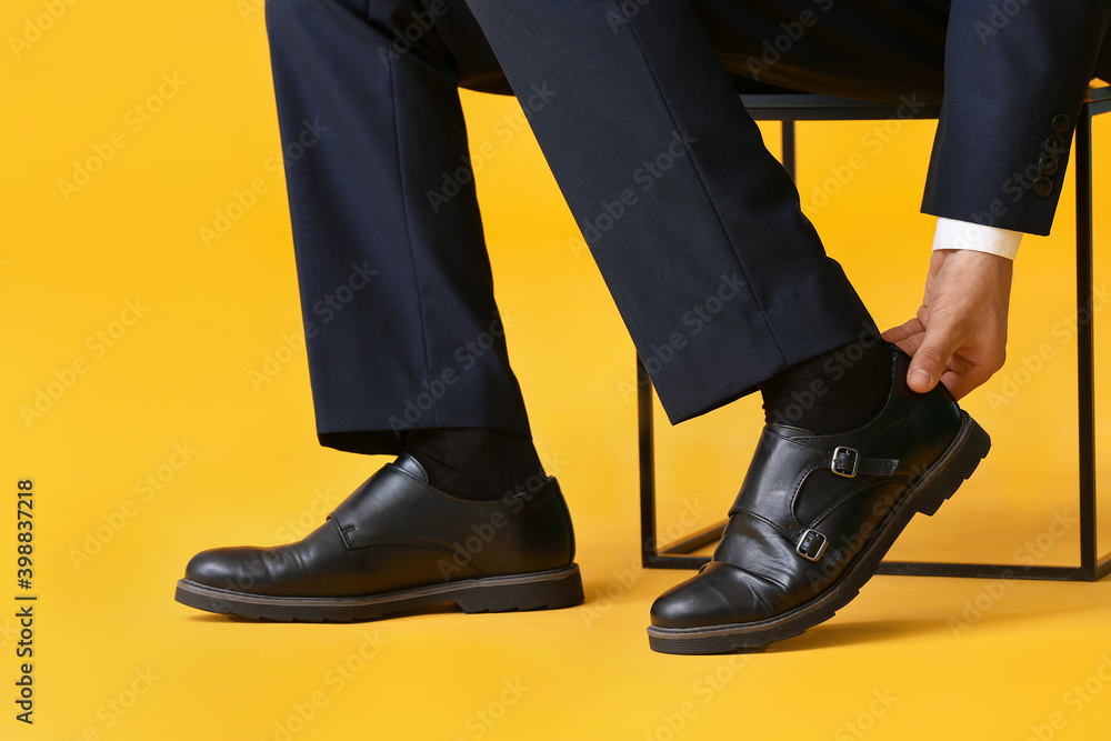 Young man in stylish shoes on color background