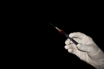 Close-up of hand of medical person with vaccine syringe isolated on black