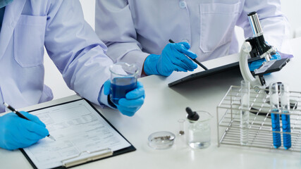 Attractive young scientist team in lab coat and safety goggles working with analysing test trial or investigations with test tubes in laboratory.