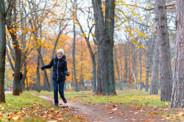 Wall Mural - teen girl and boy running through the park and enjoys autumn, beautiful nature with yellow leaves