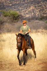 Poster - Blonde horsewoman rides towards camera in savannah