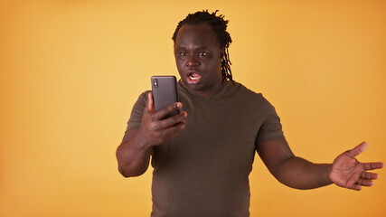 Shocked african american black man looking at the screen of his phone. Unexpected text message or bad news. High quality photo