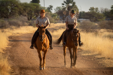 Poster - Blonde and brunette horsewomen ride along track