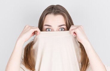 Canvas Print - Close up portrait of surprised woman in white t-shirt covering her face with a t-shirt.